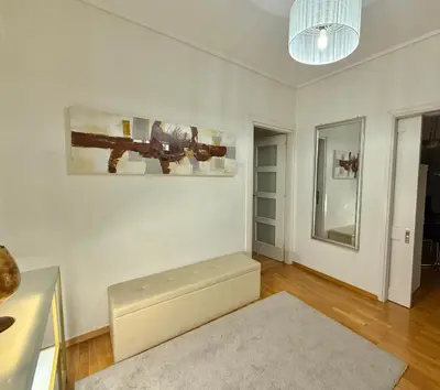 a living room with a bench and a painting on the wall at Central Glyfada 2BR Apartment in Athens