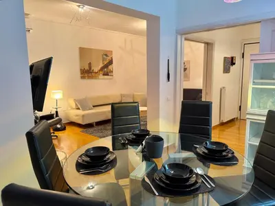 a living room with a glass table and black chairs at Central Glyfada 2BR Apartment in Athens