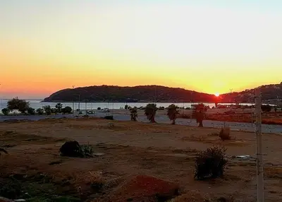 a sunset on a beach with the sun setting at Casa al Mare Anavissos in Anavissos