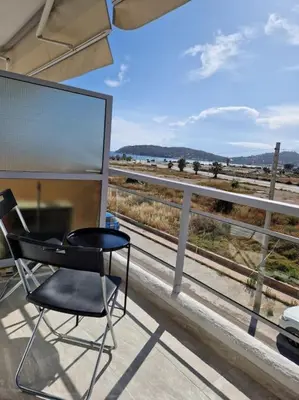 a chair on a balcony with a view of a train at Casa al Mare Anavissos in Anavissos