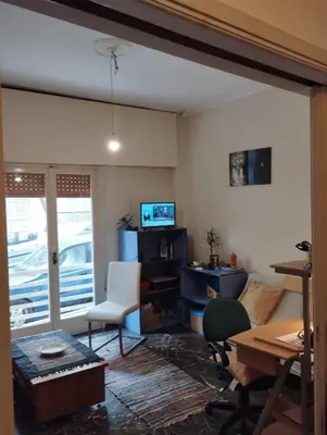 a living room with a desk and a chair and a television at Central appartement in Athens