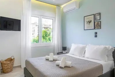 a bedroom with a bed with white sheets and a window at Central 2BR Apartment in the Heart of Athens in Athens