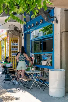 a woman sitting at a table in front of a restaurant at Central 2BR Apartment in the Heart of Athens in Athens