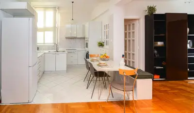 a kitchen with white cabinets and a table with chairs at Φωτεινό κομψό & άνετο διαμέρισμα κοντά στο κέντρο! in Athens