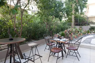 a patio with two tables and chairs and trees at The Crystal Blue Hotel in Athens