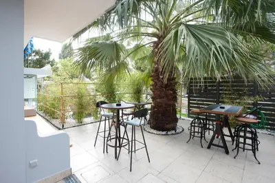 a patio with tables and chairs and a palm tree at The Crystal Blue Hotel in Athens