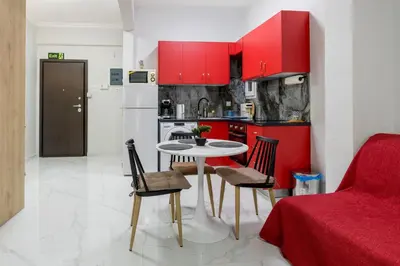 a kitchen with red cabinets and a table and chairs at Άνετο στούντιο στο κέντρο in Athens