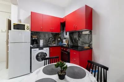 a kitchen with red cabinets and a table and a washer at Άνετο στούντιο στο κέντρο in Athens