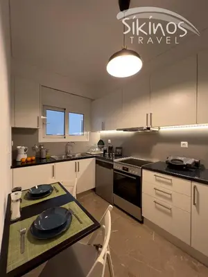 a kitchen with white cabinets and a table with plates on it at Green Oasis in the center of Athens in Athens