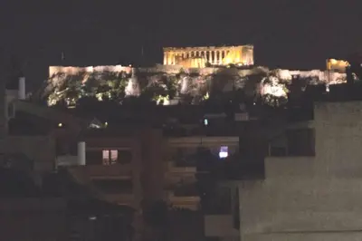 a building on top of a hill at night at Best Family House,Acropolis view,5 min from metro in Athens