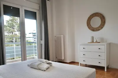 a white bedroom with a bed and a window at SynPiraeus Apartments & Studios in Piraeus