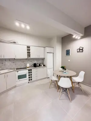 a kitchen with white cabinets and a table and chairs at Metro Chic Haven: Modernized Urban Studio near the Tram in Athens