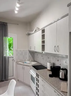a kitchen with white cabinets and a counter top at Metro Chic Haven: Modernized Urban Studio near the Tram in Athens