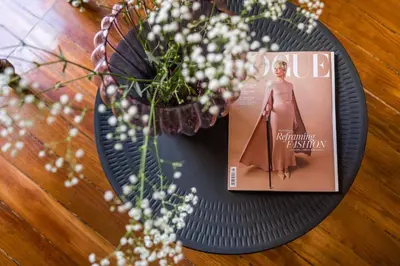 a magazine sitting on a table next to a vase of flowers at Charlie in Athens