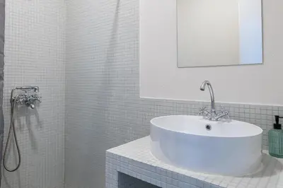 a white bathroom with a sink and a mirror at Charlie in Athens