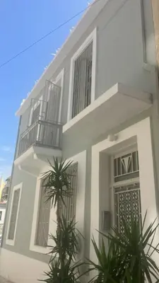 a white house with a balcony and plants in front of it at Crane in Athens
