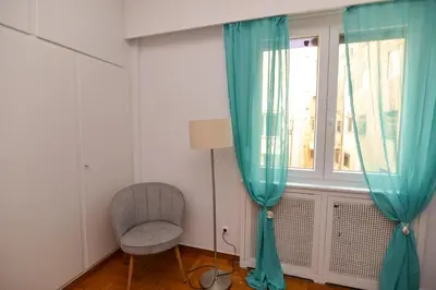 a room with a chair and a window with blue curtains at Athens central studio in front of Syntagma metro in Athens