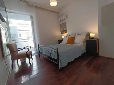 a bedroom with a bed and a chair and a window at Apartment by the Sepolia metro in Athens
