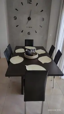a dining room table with chairs and a clock on the wall at Urbi Garden in Artemida