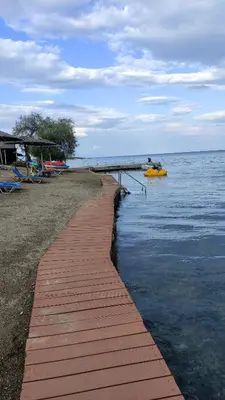 a wooden walkway leading to the water on a beach at Urbi Garden in Artemida