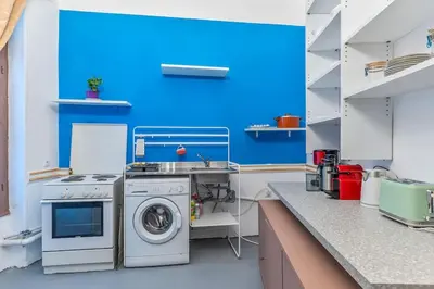 a kitchen with a washing machine and a blue wall at 4 Bedroom Vintage House in heart of Pagrati Athens in Athens