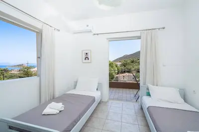 a bedroom with two beds and a large window at Omnia Maisonette by A&D Properties in Porto Rafti