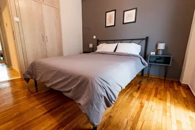 a bedroom with a large bed and a wooden floor at The Athenian Hideaway 2- Bedroom apartment in Thiseio in Athens
