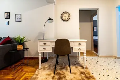 a desk with a chair and a clock on a wall at The Athenian Hideaway 2- Bedroom apartment in Thiseio in Athens