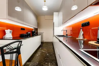 a kitchen with orange walls and white cabinets at Luxury flat at archaeological museum in Athens