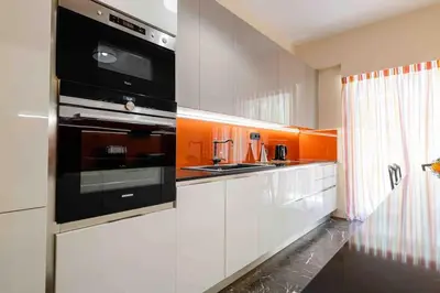 a kitchen with white cabinets and black appliances at Luxury flat at archaeological museum in Athens
