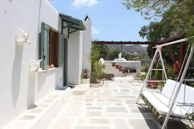 a patio with a swing next to a white building at Aegean traditional home in Athens Riviera in Sounio