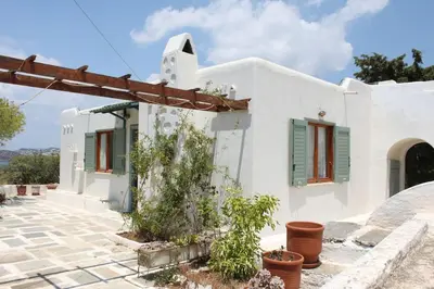 a white house with green shuttered windows and plants at Aegean traditional home in Athens Riviera in Sounio
