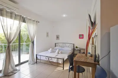 a bedroom with a bed and a table and a balcony at Glyfada Cozy Studio, WiFi, AC in Athens