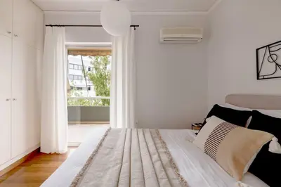 a bedroom with a bed with white walls and a window at Smart Chic 1BR Apartment in Agia Paraskevi by UPSTREET in Athens