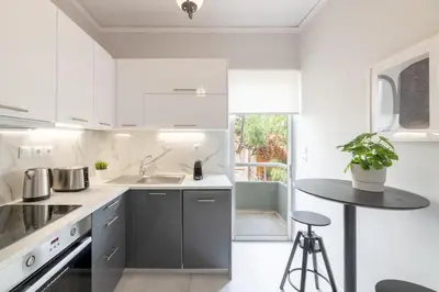 a white kitchen with a sink and a table at Smart Chic 1BR Apartment in Agia Paraskevi by UPSTREET in Athens