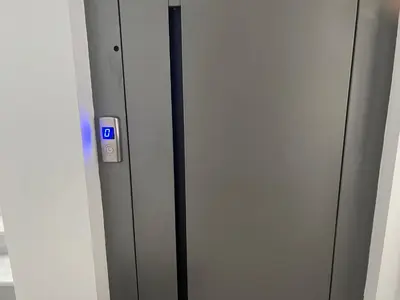 a elevator with a blue button on a wall at Elia's Apartment in Athens