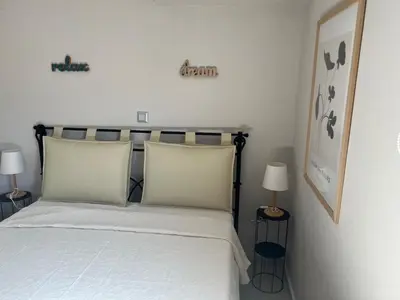 a bedroom with a bed with white sheets and two lamps at Elia's Apartment in Athens