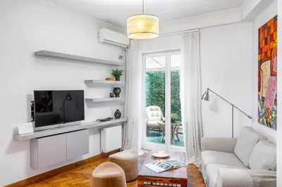 a white living room with a couch and a tv at Central Athenian 1BR Apartment in Athens