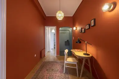 a hallway with orange walls and a desk and a lamp at A new happy 2 BDR apartment that has a soul in Athens
