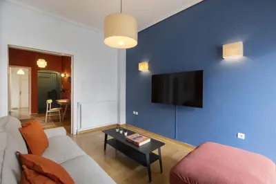 a living room with a couch and a tv on a blue wall at A new happy 2 BDR apartment that has a soul in Athens