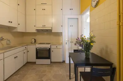a kitchen with white cabinets and a table with flowers on it at A new happy 2 BDR apartment that has a soul in Athens