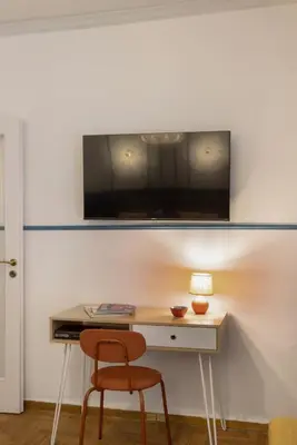 a desk with a chair and a television on a wall at AnapironPolemou5 - Elegance meets charm in a posh in Athens