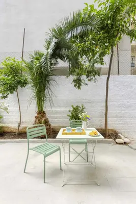 a table and two chairs next to a table and trees at AnapironPolemou5 - Elegance meets charm in a posh in Athens