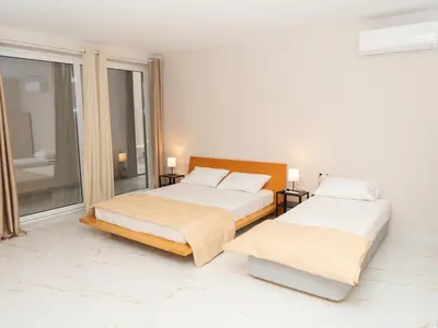 two beds in a white room with a window at ALLAGIANNIS GROUP APARTMENTS in Markopoulo