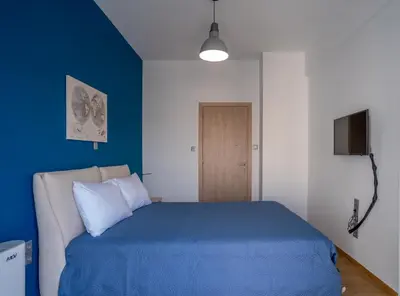 a bedroom with a blue bed and a television at Maxblue 2 in Piraeus