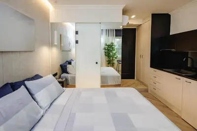 a bedroom with a large white bed and a kitchen at Triple A @ Trendy Psiri - Art & Nightlife in Athens