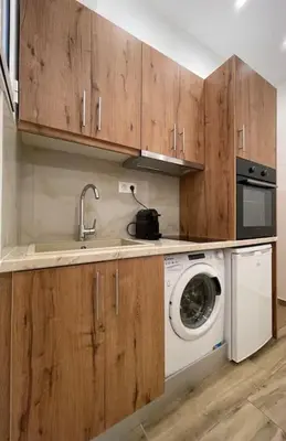 a kitchen with a washing machine and wooden cabinets at Pagrati-Brand new luxury central studio in Athens