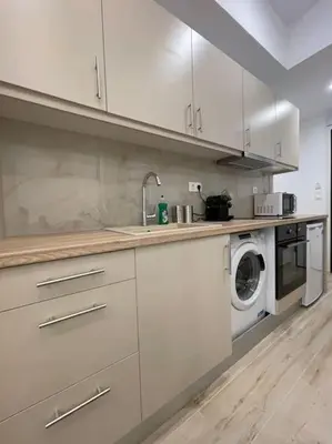 a kitchen with white cabinets and a washing machine at Pagrati-Luxury central cozy studio in Athens