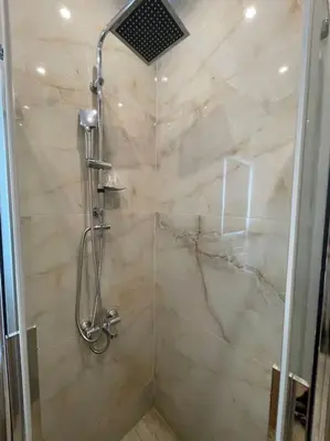 a bathroom with a shower with a marble wall at Pagrati-Luxury central cozy studio in Athens