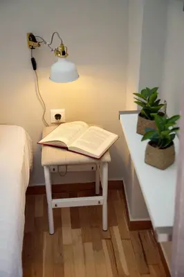 a bedside table with a book and a lamp on it at Aroura Homes 2BR Central Balcony Apt Metro in Athens